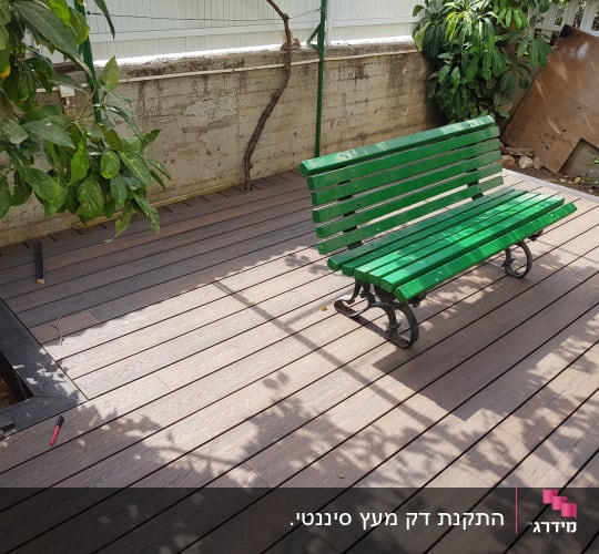 ספסל ירוק על דק עץ בגינה